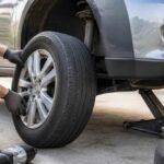 Mechanik wymienia koło w samochodzie podniesionym na podnośniku hydraulicznym